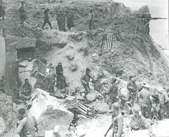 Rudder's command post on Pointe du Hoc, late morning, June 8, 1944. Rudder is at top center, watching the German prisoners. Photo courtesy of the U.S. National Archives. Rudder's Command Post
